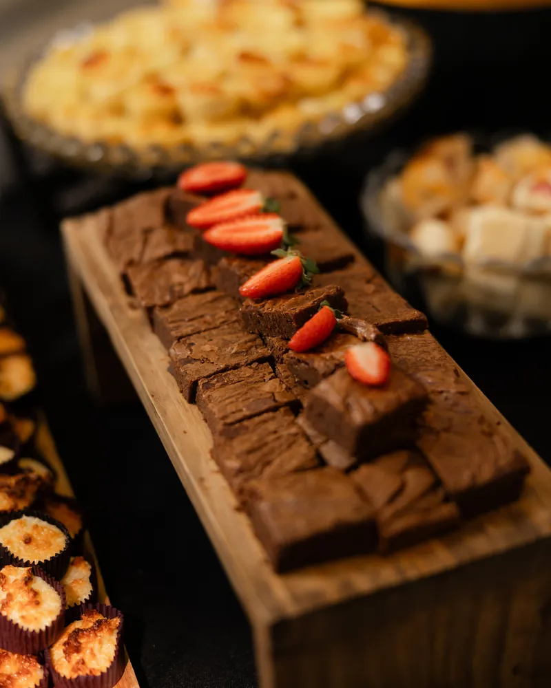Brownies decorados com morangos sobre uma tábua de madeira, numa mesa montada pela Coffice