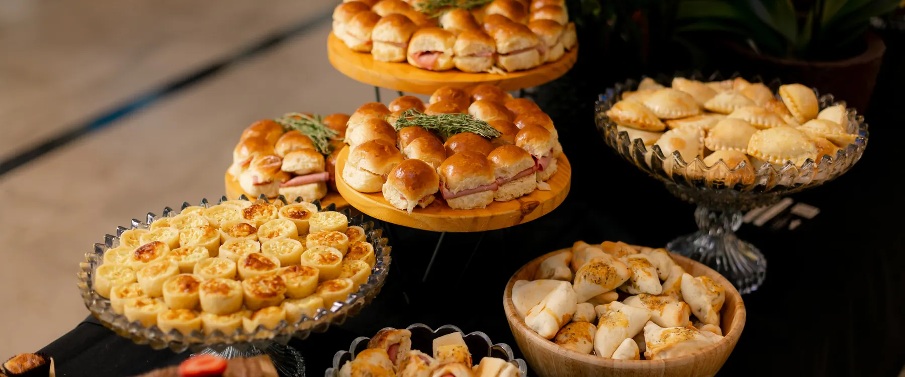 Mesa de coffee break vista de cima, com mini sanduíches, quiches, empadas e folhados
